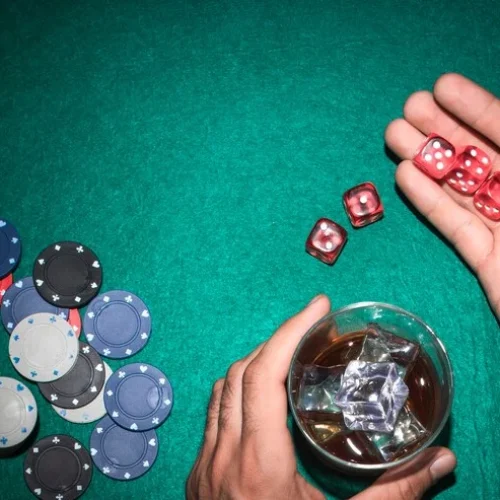 poker-player-showing-red-dices-with-glass-whiskey-poker-table_23-2147881222
